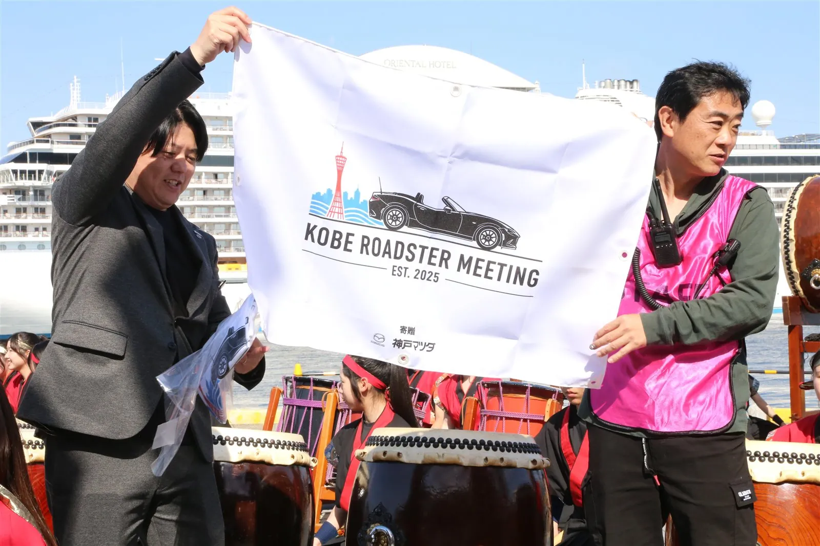Staff holding up the KOBE ROADSTER MEETING flag